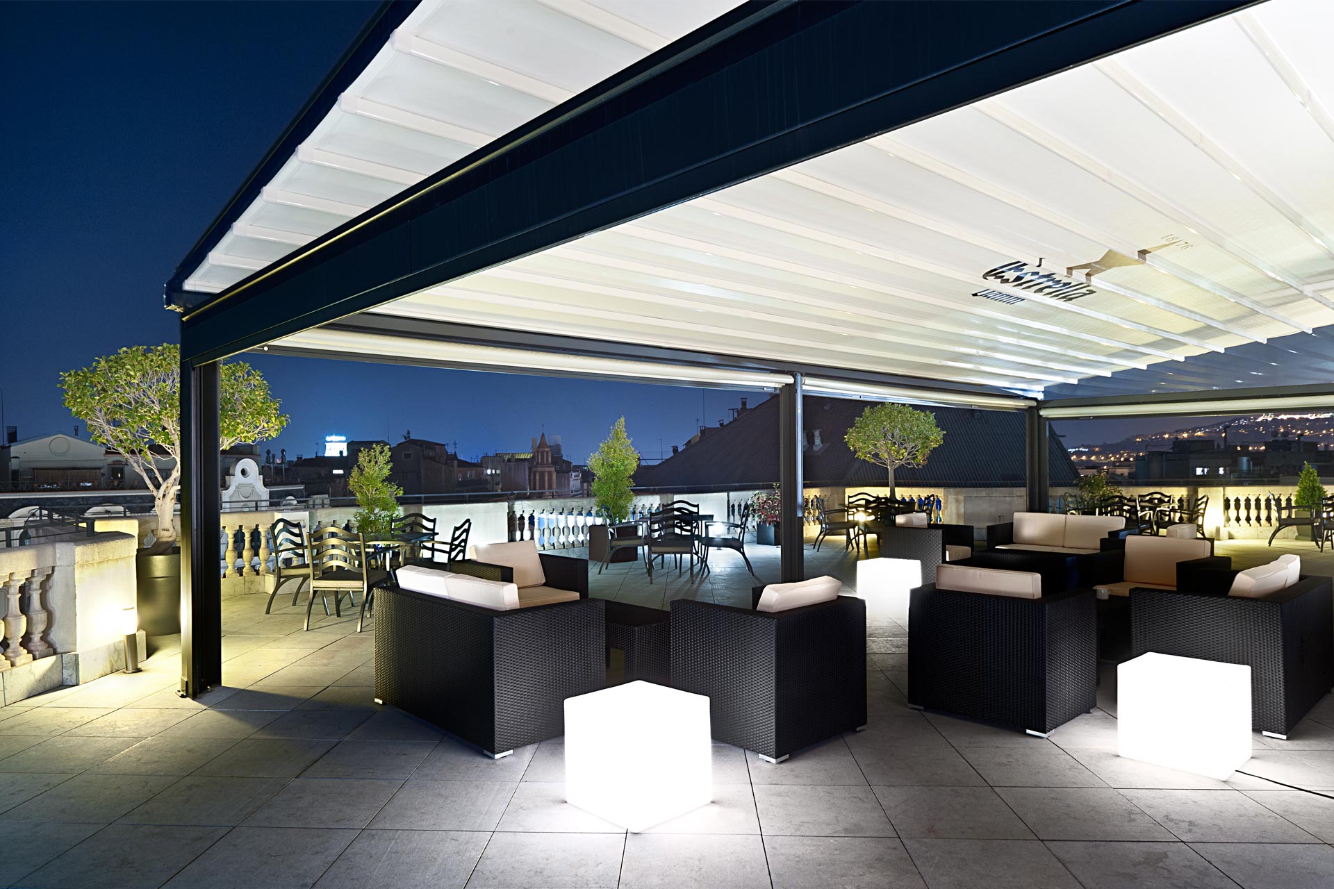 Pérgola cubriendo terraza con mobiliario exterior de noche en Hotel Center