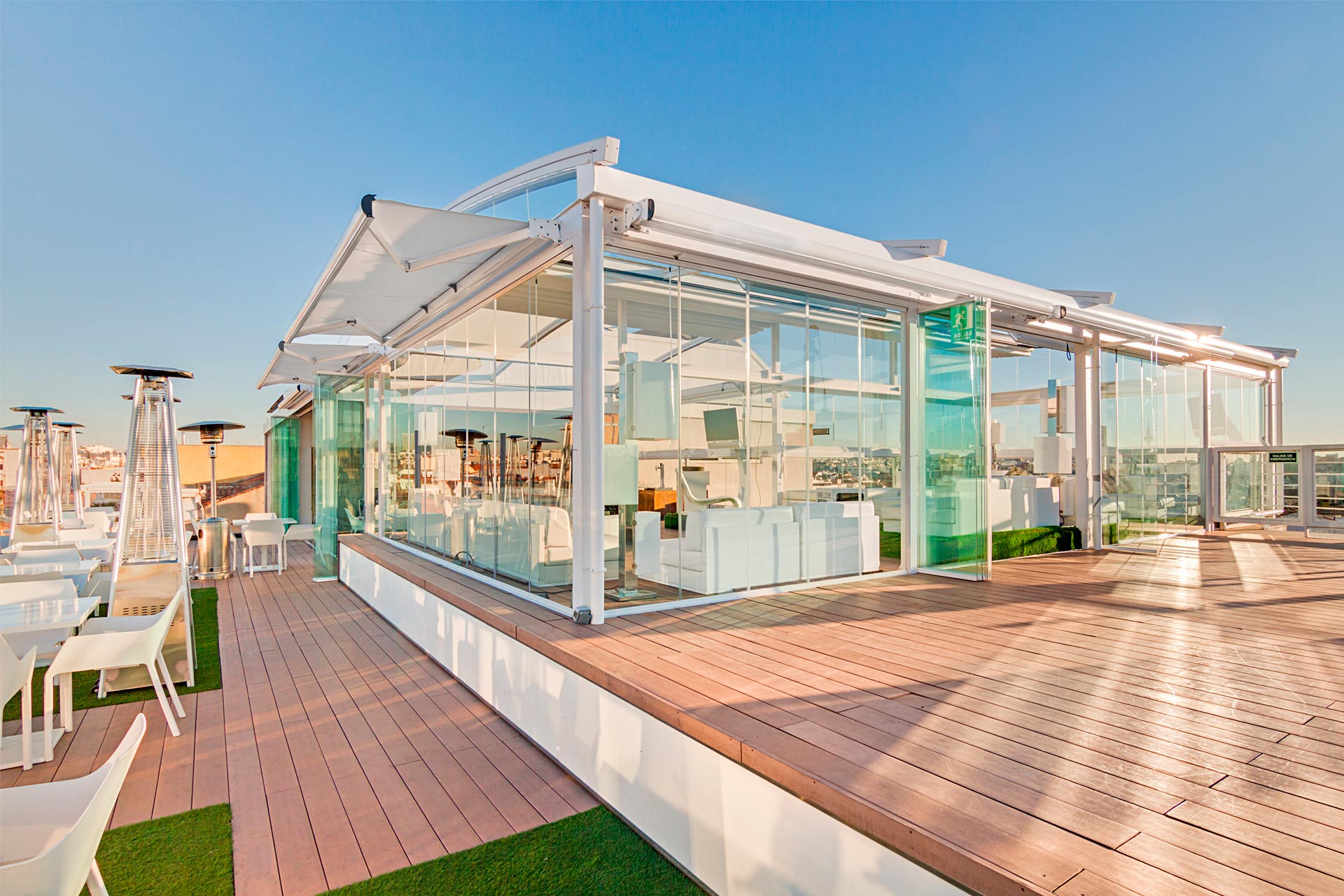 Pérgola con cerramientos de cristal en tarima de madera en la terraza del Hotel Oscar