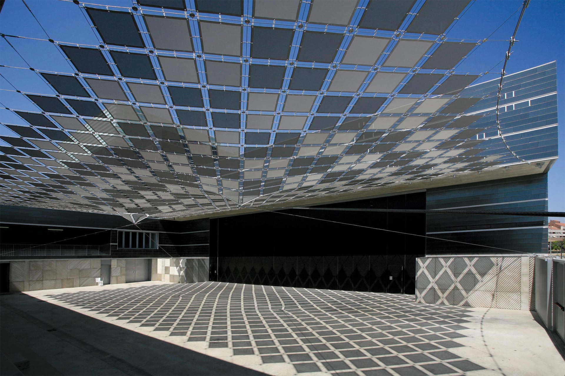 Estructura tensada con rombos grises y negros cubriento la terraza del palacio de los congresos de h