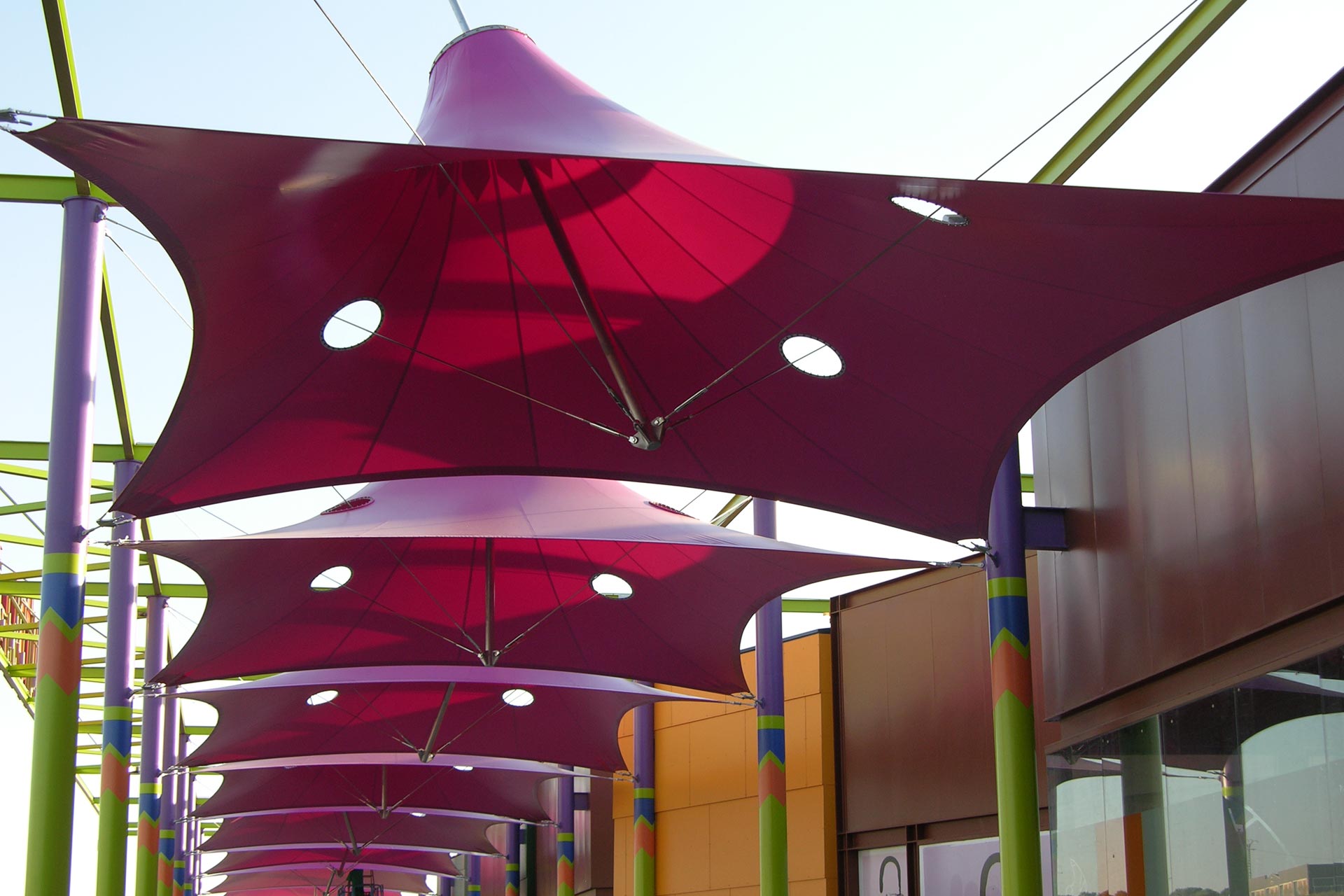 Estructura tensada en forma de parasol de color rojo en centro comercial Puerta toledo