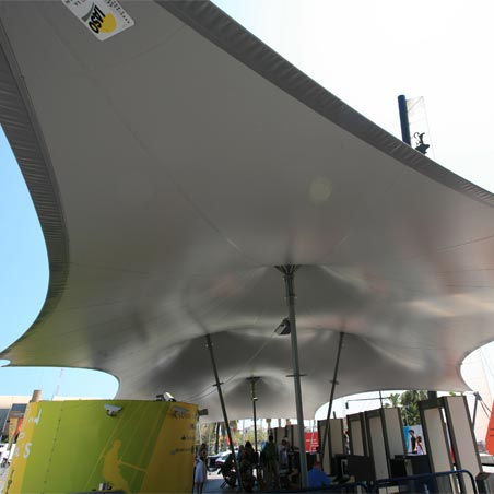 Estructura tensada en forma de carpa de circo con lona gris cubriendo equipamientos