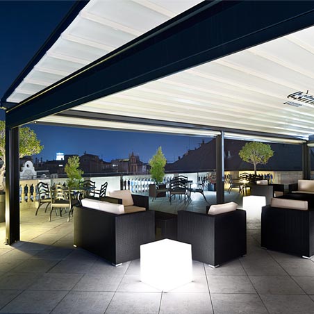 Pérgola cubriendo terraza con mobiliario exterior de noche en Hotel Center