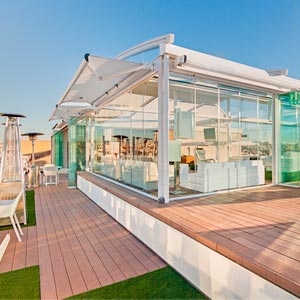 Pérgola con cerramientos de cristal en tarima de madera en la terraza del Hotel Oscar
