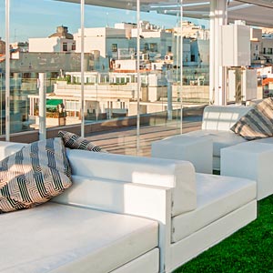 Mobiliario blanco para exterior en pérgola con cerramientos de cristal en Hotel Oscar