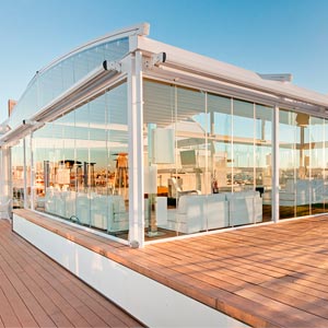 Pérgola con cerramientos de cristal en tarima de madera en la terraza del Hotel Oscar