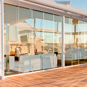 Pérgola con cerramientos de cristal en tarima de madera en la terraza del Hotel Oscar
